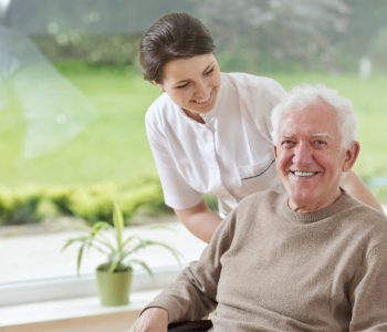 caregiver and elderly man in a wheelchair smiling
